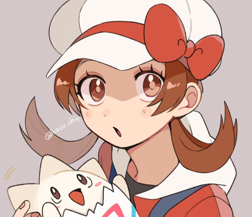 1girl :o blush_stickers bow brown_eyes brown_hair cabbie_hat eyelashes grey_background hat hat_bow highres holding holding_pokemon long_hair looking_at_viewer lyra_(pokemon) momotose_(hzuu_xh4) pokemon pokemon_(creature) pokemon_(game) pokemon_hgss red_bow red_shirt shirt togepi twintails twitter_username upper_body white_headwear