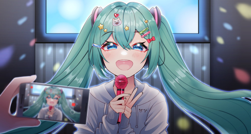 1girl 1other bangs blue_eyes blurry blurry_foreground bow copyright_request eyebrows_visible_through_hair green_hair grey_hoodie hair_bow hair_ornament hairclip hands_up highres holding holding_microphone holding_phone hood hood_down hoodie long_hair long_sleeves masumofu microphone nail_polish phone red_nails shiny shiny_hair solo_focus star_(symbol) star_hair_ornament taking_picture twintails
