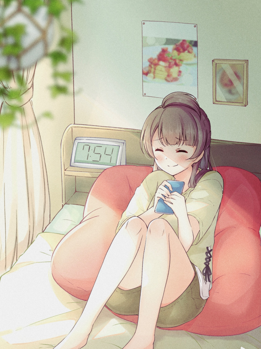 1girl bangs bed bedroom blunt_bangs blurry blurry_foreground blush brown_hair brown_shirt brown_shorts clock closed_eyes commentary cushion hair_tuft happy highres holding holding_phone indoors knees_up long_hair love_live! love_live!_school_idol_project minami_kotori on_bed phone picture_frame poster_(object) satisfaction-zero shade shirt short_sleeves shorts sitting sitting_on_bed smile solo
