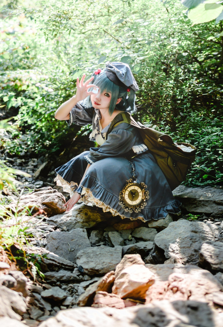 1girl backpack bag between_legs blue_dress blue_eyes blue_hair blue_headwear blurry blurry_background bokeh clock collarbone cosplay cosplay_photo covering_one_eye day depth_of_field dress flat_cap frilled_dress frilled_sleeves frills full_body grass green_bag hair_between_eyes hair_bobbles hair_ornament hand_between_legs hat head_tilt highres karryyu930 kawashiro_nitori kawashiro_nitori_(cosplay) leaf looking_at_viewer medium_hair mixed-language_commentary nature outdoors peeing photo_(medium) puffy_short_sleeves puffy_sleeves river rock short_sleeves smile solo stream touhou tree twintails water wig