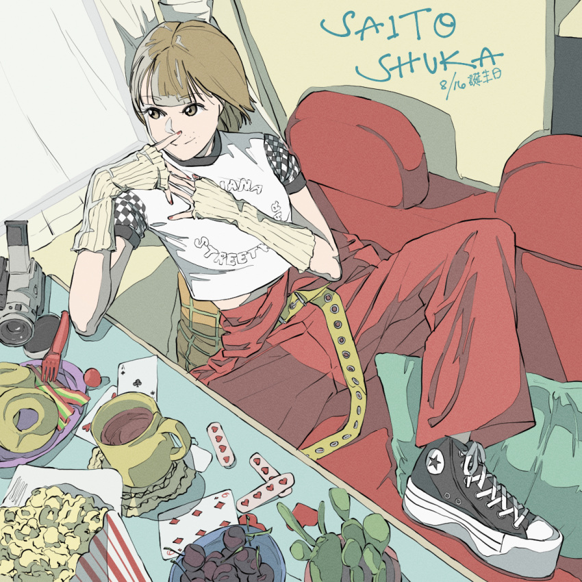 1girl bangs birthday brown_eyes brown_hair card character_name commentary cup curtains dated doughnut elbow_gloves english_text fingerless_gloves food fork gloves mug playing_card popcorn real_life red_nails rei_(yousuru_) saitou_shuka short_hair sitting solo table video_camera