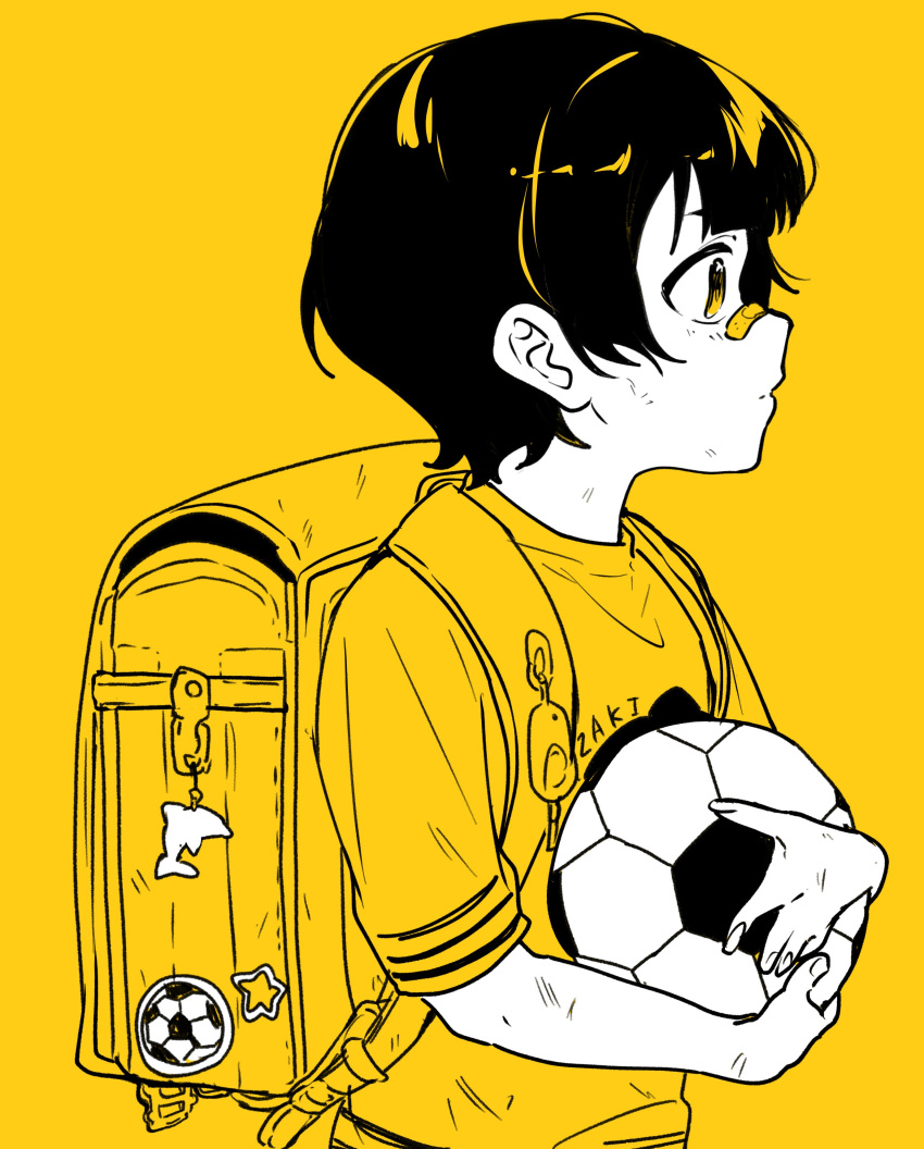 1boy absurdres aged_down bachira_meguru backpack bag bag_charm ball bandaid bandaid_on_face bandaid_on_nose bangs blue_lock charm_(object) child from_side highres holding holding_ball male_child male_focus monochrome pepupapipooo randoseru shirt short_hair short_sleeves simple_background soccer_ball solo upper_body yellow_background yellow_theme