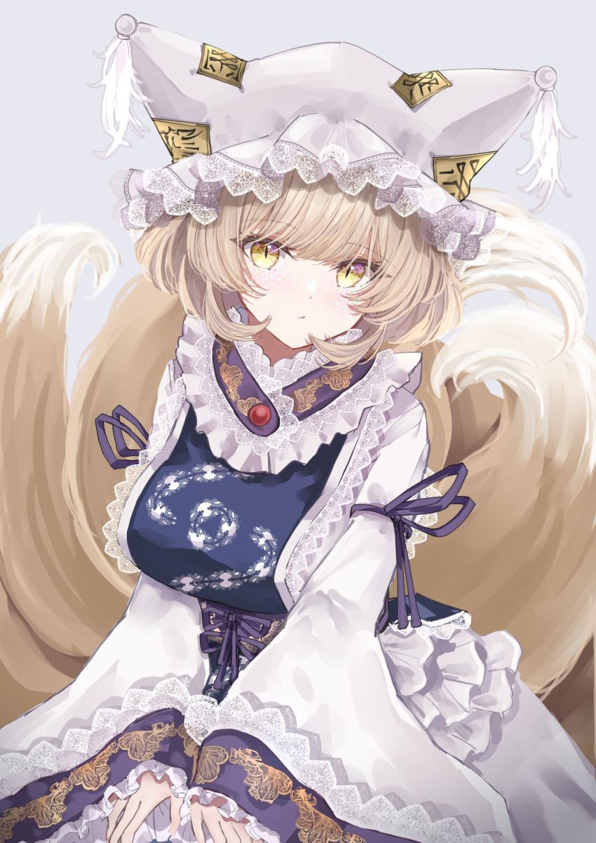 1girl bangs blonde_hair blue_tabard closed_mouth commentary_request cowboy_shot dress fox_tail frilled_sleeves frills hat highres lace-trimmed_headwear lace-trimmed_sleeves lace_trim long_sleeves looking_at_viewer medium_hair mob_cap multiple_tails purple_ribbon ribbon sarasadou_dan slit_pupils solo tabard tail touhou white_dress white_headwear wide_sleeves yakumo_ran yellow_eyes