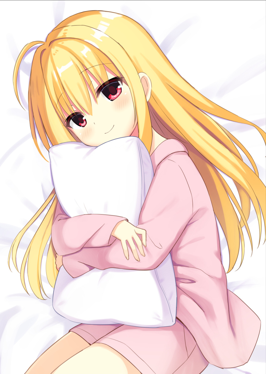 1girl ahoge bed_sheet blonde_hair blush closed_mouth cowboy_shot crossed_arms double-parted_bangs eyelashes eyes_visible_through_hair hair_between_eyes hair_down hamidashi_creative highres izumi_hiyori long_hair long_sleeves looking_at_viewer lying object_hug on_side pajamas pillow pillow_hug pink_pajamas red_eyes sidelocks smile solo utsunomiya_tsumire