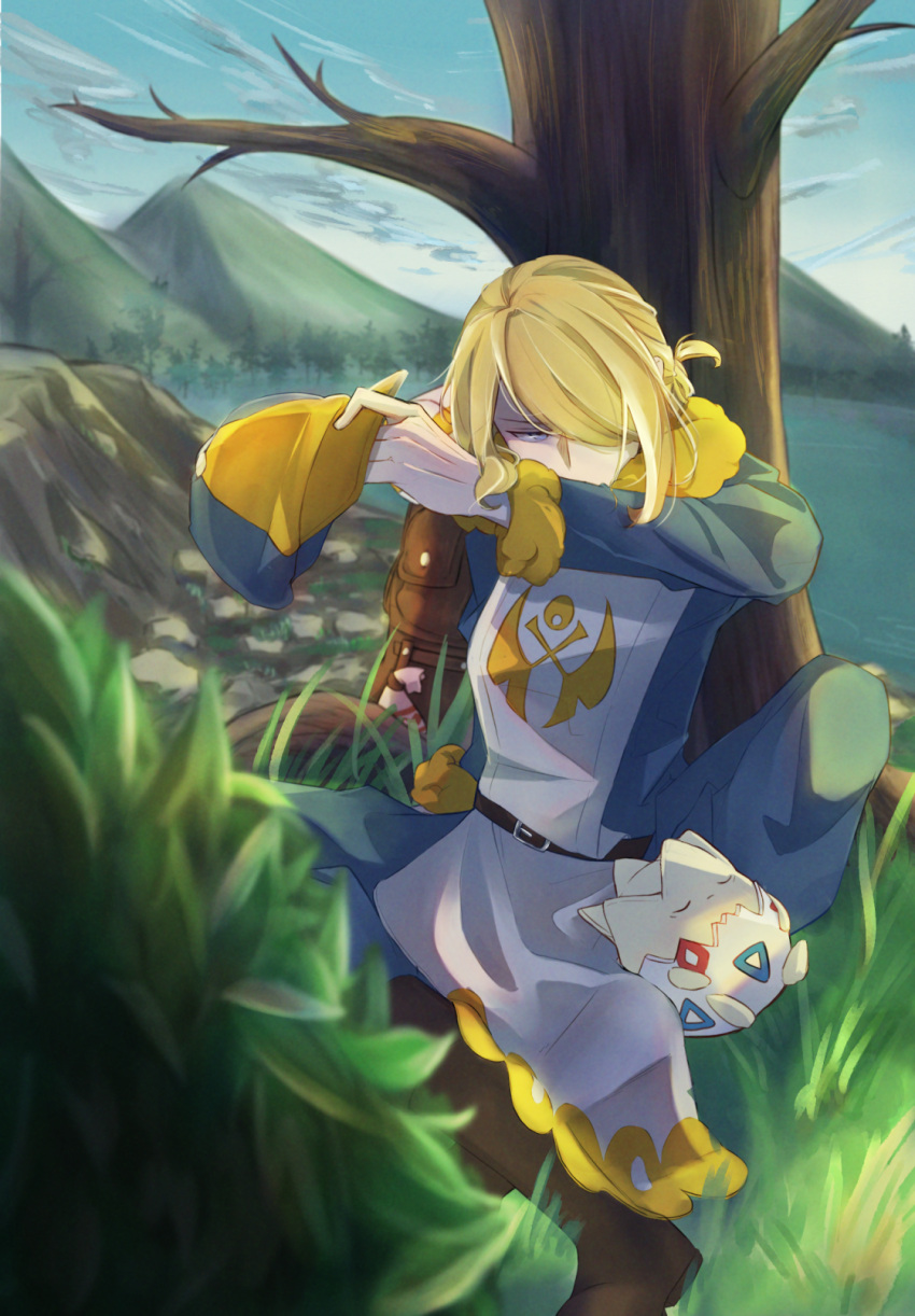 1boy against_tree bare_tree belt blonde_hair blurry blurry_foreground boots brown_bag brown_footwear bush day grass hair_over_one_eye hat hat_removed headwear_removed highres holding holding_clothes holding_hat jumpsuit long_sleeves male_focus nirugiri_(nirgy) outdoors pokemon pokemon_(creature) pokemon_(game) pokemon_legends:_arceus sitting togepi tree volo_(pokemon)