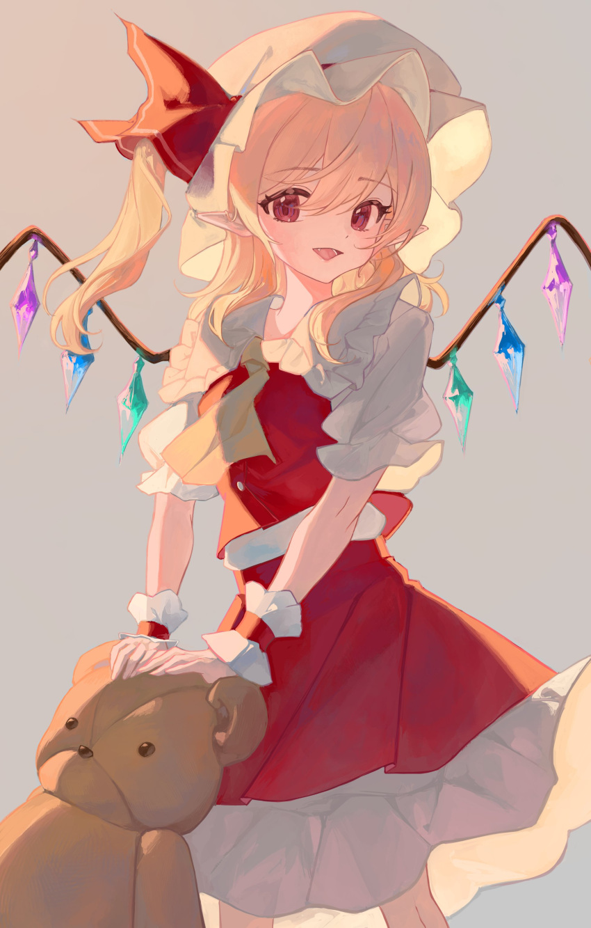 1girl :d absurdres bare_legs blonde_hair breasts crystal feet_out_of_frame flandre_scarlet frilled_shirt_collar frills grey_background hair_between_eyes hat highres holding holding_stuffed_toy long_hair looking_at_viewer mob_cap open_mouth petite petticoat red_eyes red_skirt red_vest sidelighting simple_background skirt skirt_set small_breasts smile solo standing stuffed_animal stuffed_toy swept_bangs teddy_bear touhou vest wings