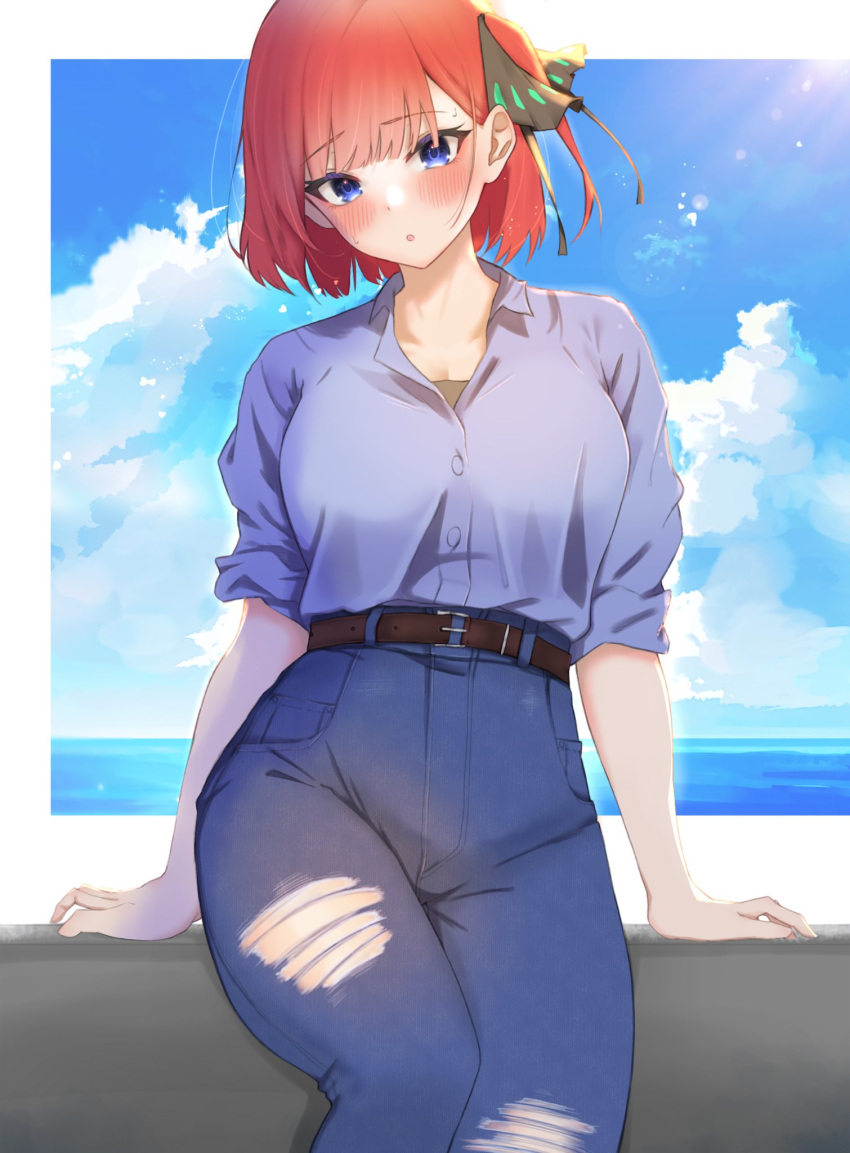 1girl arms_at_sides belt blue_eyes blue_shirt blush breasts butterfly_hair_ornament denim go-toubun_no_hanayome hair_ornament head_tilt high-waist_pants highres jeans kakato_0 large_breasts looking_at_viewer nakano_nino ocean pants parted_lips redhead shirt sitting sky solo torn_clothes torn_jeans torn_pants
