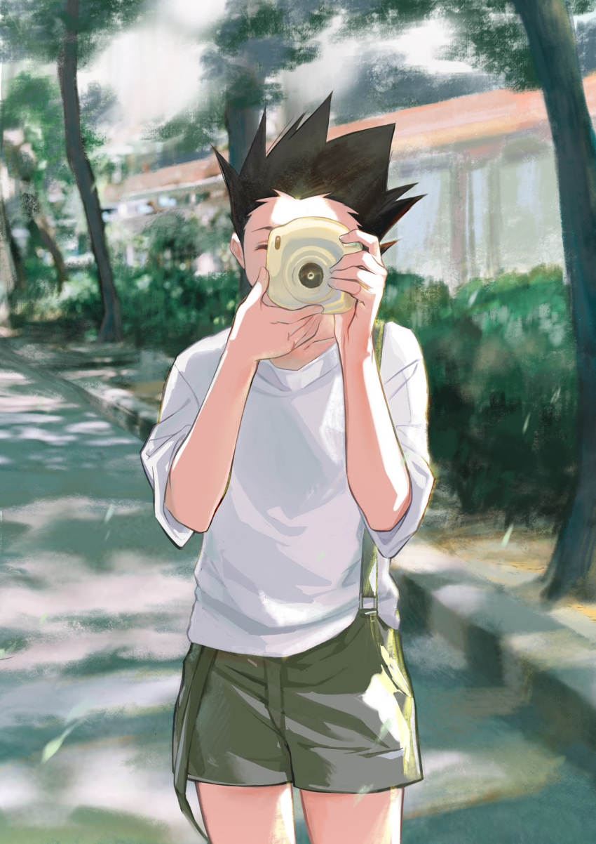 1boy black_hair camera cowboy_shot day gon_freecss green_overalls highres holding holding_camera hunter_x_hunter k.g_(matsumoto_zo) male_focus one_eye_closed outdoors overall_shorts overalls shirt short_hair solo spiky_hair standing taking_picture tree white_shirt