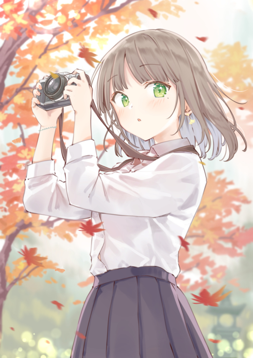 1girl :o autumn autumn_leaves blurry blurry_background blush brown_hair brown_skirt camera camera_around_neck collared_shirt colored_inner_hair commentary cowboy_shot dot_nose falling_leaves green_eyes grey_hair highres holding holding_camera leaf long_sleeves looking_at_viewer maigoyaki maple_leaf multicolored_hair original outdoors pleated_skirt shirt skirt solo symbol-only_commentary tree white_shirt