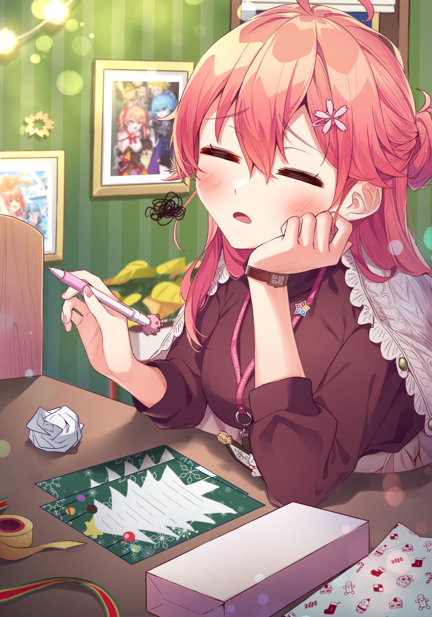 1girl =_= absurdres ahoge alternate_costume black_shirt blush christmas closed_eyes commentary crumpled_paper elbow_rest hair_between_eyes hands_up head_rest highres holding holding_pen hololive hoshimachi_suisei indoors lanyard long_hair long_sleeves open_mouth pen photo_(object) pink_hair sakura_miko scribble shirt solo table tang-du upper_body virtual_youtuber watch watch wrapping_paper