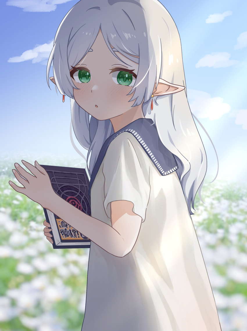 1girl 8_nana_usagi blue_sky blurry blurry_background book clouds commentary_request day depth_of_field earrings elf field flower flower_field frieren green_eyes highres holding holding_book jewelry long_hair looking_at_viewer outdoors parted_bangs parted_lips pointy_ears shirt short_sleeves sky solo sousou_no_frieren white_hair white_shirt