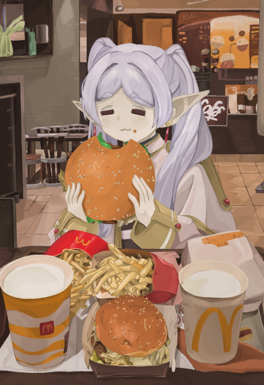 1girl :3 =_= burger capelet cup dangle_earrings disposable_cup earrings eating elf food food_on_face french_fries frieren gold_trim hands_up highres holding holding_burger holding_food indoors jewelry long_sleeves mcdonald's naaga_sonomono parted_bangs photo_background pointy_ears restaurant sitting sleeve_cuffs solo sousou_no_frieren twintails white_capelet white_hair