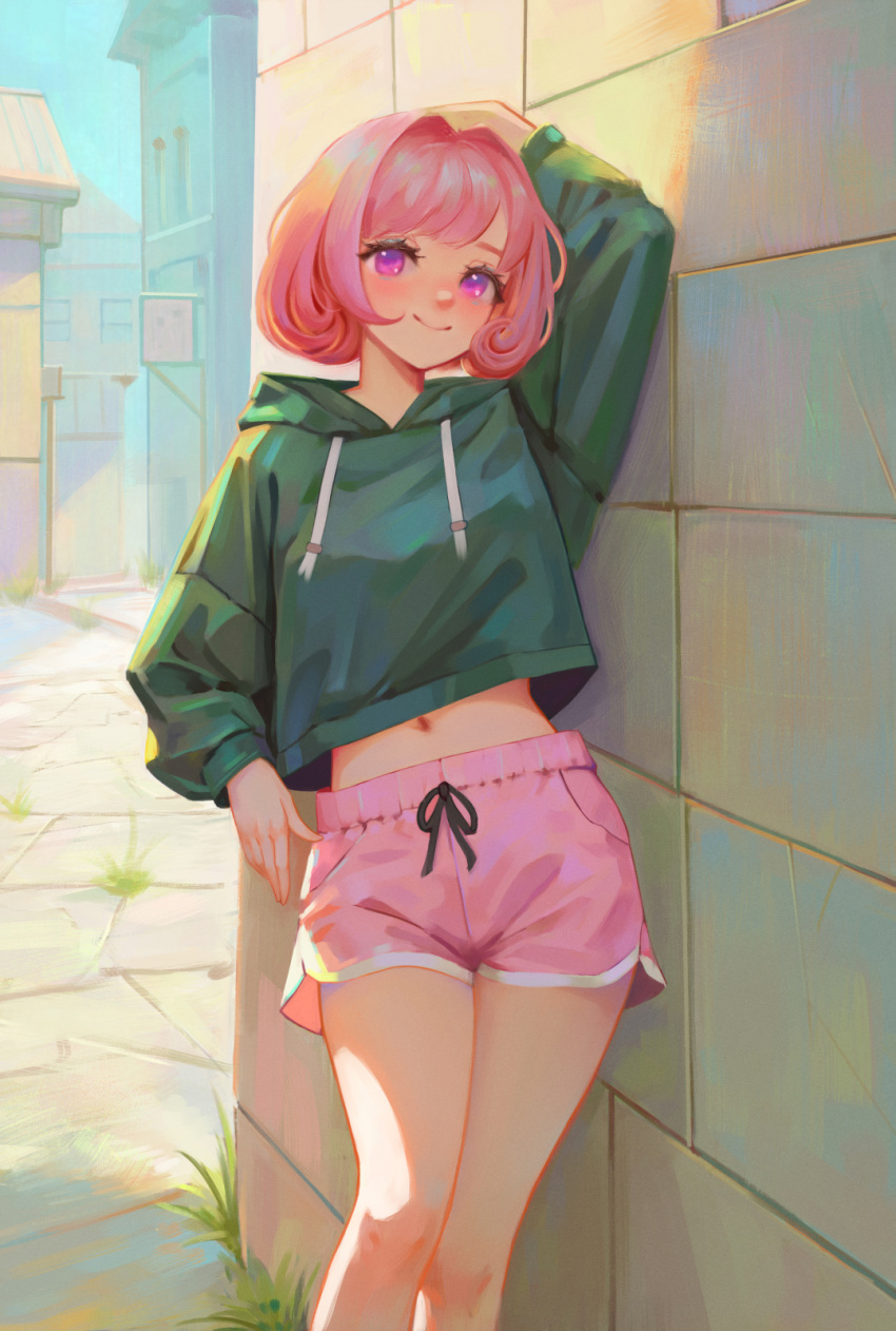1girl arm_at_side arm_up blush bob_cut building closed_mouth commentary cropped_hoodie dolphin_shorts drawstring english_commentary eyelashes grass green_hoodie highres hood hood_down hoodie leaning long_sleeves looking_at_viewer midriff navel original outdoors pink_eyes pink_hair pink_shorts shchrit short_hair short_shorts shorts sign smile solo standing stone_floor stone_wall town