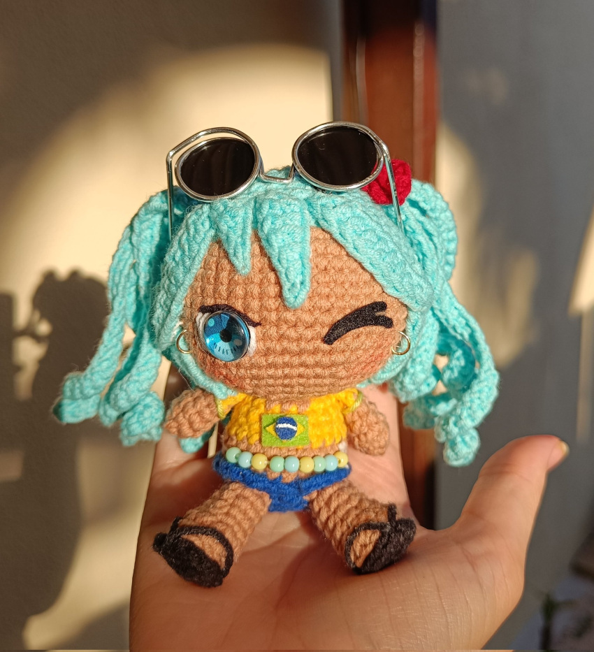 1girl aqua_eyes aqua_hair belly_chain black_footwear blue_shorts brazilian_flag brazilian_flag_print brazilian_miku chibi dibielyy doll earrings eyewear_on_head flip-flops flower hair_flower hair_ornament hatsune_miku highres jewelry one_eye_closed photo_(medium) print_shirt red_flower sandals shadow shirt short_sleeves shorts solo sunglasses twintails unconventional_media vocaloid yellow_shirt