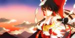  1girl ascot black_hair blurry bow depth_of_field hair_bow hair_ornament hair_ribbon hair_tubes hakurei_reimu koyubi_right long_hair looking_at_viewer mountain red_eyes ribbon rope shimenawa solo touhou twilight 