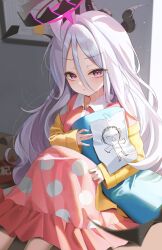  1girl absurdres black_halo black_horns blue_archive blush cardigan closed_mouth commentary dakimakura_(object) doodle_sensei_(blue_archive) hair_between_eyes halo highres hina_(blue_archive) hina_(pajamas)_(blue_archive) holding holding_pillow horns long_hair looking_at_viewer luz0207 official_alternate_costume pajamas paper pillow pink_pajamas sensei_(blue_archive) sitting solo tape very_long_hair violet_eyes white_hair yellow_cardigan 