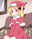  1girl blonde_hair capelet commentary couch dress flandre_scarlet hair_ribbon hammer_(sunset_beach) hat open_mouth red_dress red_eyes ribbon santa_costume santa_hat short_hair side_ponytail sitting solo touhou wings 