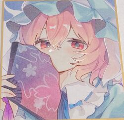  1girl blue_hat blue_kimono commentary folding_fan hand_fan hat highres holding holding_fan japanese_clothes kimono long_sleeves looking_at_viewer medium_hair mob_cap moni_monico photo_(medium) pink_eyes pink_hair portrait ribbon-trimmed_collar ribbon_trim saigyouji_yuyuko shikishi solo touhou traditional_media untranslatable_commentary 