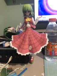  1girl ahoge ascot closed_mouth collared_shirt full_body green_hair grid_print hand_up highres kazami_yuuka long_skirt long_sleeves looking_ahead medium_hair papercraft_(medium) photo_(medium) red_skirt red_vest shirt shirt_tucked_in skirt slackmeisster1 smile solo standing touhou unconventional_media vest white_shirt yellow_ascot 