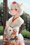  1girl 2016 alternate_costume animal_ears blush cowboy_shot day fingers_together floral_print fur_collar hair_between_eyes happy_new_year hat highres inubashiri_momiji japanese_clothes kimono long_sleeves looking_down new_year obi outdoors print_kimono red_eyes ribbon rikapo sash short_hair smile solo sunlight tail tokin_hat touhou translated tree white_hair wide_sleeves wolf_ears wolf_tail 