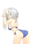  1girl against_wall ass back bikini blue_bikini breasts grey_eyes hair_ornament hairclip hamakaze_(kantai_collection) highres kantai_collection large_breasts leaning_forward looking_at_viewer mouth_hold ootsuki_momiji ribbon_in_mouth side-tie_bikini sideboob silver_hair smile solo swimsuit untied untied_bikini 