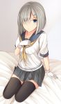  1girl :o arm_support black_legwear blue_eyes blush breasts commentary_request eyes_visible_through_hair full_body gloves grey_skirt hair_ornament hair_over_one_eye hairclip hamakaze_(kantai_collection) highres kanpyo_(hghgkenfany) kantai_collection large_breasts looking_at_viewer neckerchief on_bed pleated_skirt school_uniform serafuku short_hair short_sleeves silver_hair sitting skirt solo thigh-highs white_gloves yokozuwari 
