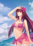  1girl adapted_costume bare_shoulders bikini blue_sky breasts brown_hair cleavage clouds cloudy_sky collarbone cowboy_shot fate/grand_order fate_(series) flower hair_flower hair_ornament hand_to_head hand_up hibiscus highres large_breasts long_hair looking_away mao_mao_wansui midriff navel ocean open_mouth outdoors purple_bikini red_eyes sarong scathach_(fate/grand_order) sidelocks sky smile solo stomach swimsuit under_boob water 