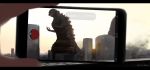  10s cellphone city godzilla godzilla_(series) hands hettsuaa highres kaijuu monster out_of_frame phone pokemon pokemon_go shin_godzilla smartphone teeth 