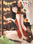  1girl animal_ears ayu_(sweetfish_man) barefoot beads bell black_hair blurry blurry_background bun_cover cat_ears cat_tail curtains dress fang full_body highres indoors jingle_bell long_hair looking_at_viewer open-back_dress open_mouth original pillow red_dress sitting solo tail yellow_eyes 