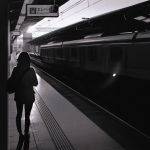  1girl greyscale ground_vehicle ilya_kuvshinov monochrome original railroad_tracks short_hair solo train train_station 