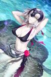  1girl ahoge arms_behind_head arms_up artist_name bangs bikini black_bikini breasts cleavage commentary_request fate/grand_order fate_(series) flower grin hands_in_hair headpiece jeanne_alter kousaki_rui large_breasts looking_at_viewer looking_to_the_side navel pale_skin partially_submerged rose ruler_(fate/apocrypha) sarong short_hair signature silver_hair smile solo swimsuit water water_drop yellow_eyes 