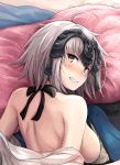  1girl ahoge back bangs bare_back bare_shoulders bed_sheet blush breasts clenched_teeth embarrassed fate/grand_order fate_(series) from_above from_behind headpiece highres hika_(hikara) jeanne_alter large_breasts looking_at_viewer looking_back lying on_stomach pillow ruler_(fate/apocrypha) short_hair shoulder_blades silver_hair solo sweat teeth twisted_neck upper_body 