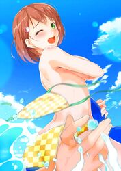  1girl ass bikini blush breasts brown_hair checkered checkered_bikini commentary_request green_eyes hair_ornament highres looking_at_viewer looking_back medium_breasts ocean one_eye_closed open_mouth original short_hair sideboob swimsuit uzuki_hiro wardrobe_malfunction 