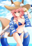  1girl animal_ears bikini blue_bikini breasts cross_(crossryou) fate/grand_order fate_(series) fox_ears fox_tail hat large_breasts legs_crossed long_hair looking_at_viewer navel pink_hair solo standing swimsuit tail tamamo_(fate)_(all) tamamo_no_mae_(swimsuit_lancer)_(fate) umbrella water yellow_eyes 