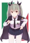  1girl anchovy bangs belt black_cape black_neckwear black_ribbon black_skirt blurry blurry_background cai_geng cape commentary cowboy_shot dress_shirt drill_hair emblem eyebrows_visible_through_hair flag_background girls_und_panzer green_hair grin hair_ribbon hand_on_hip holding italian_flag leaning_forward long_hair long_sleeves looking_at_viewer miniskirt necktie pantyhose pleated_skirt red_eyes ribbon riding_crop school_uniform shirt skirt smile solo standing twin_drills twintails twitter_username white_legwear white_shirt 