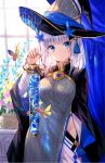  1girl blue_eyes butterfly eyebrows_visible_through_hair flower fuji_choko hair_flower hair_ornament hat highres looking_at_viewer mole mole_under_eye original short_hair solo white_hair wizard_hat 