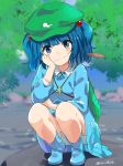  1girl bangs blue_dress blue_eyes blue_footwear blue_hair blunt_bangs blurry blurry_background boots cat_teaser commentary_request dress eyebrows_visible_through_hair green_hat hair_bobbles hair_ornament hand_up hat ica kawashiro_nitori key long_sleeves looking_at_viewer mouth_hold outdoors short_hair simple_background smile solo squatting touhou twintails twitter_username 