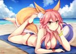  1girl animal_ears arm_support ball bangs bare_legs bare_shoulders barefoot beach beachball bikini blue_bikini blue_sky blush breasts brown_eyes chrisandita cleavage closed_mouth clouds cloudy_sky day eyebrows_visible_through_hair fate/grand_order fate_(series) fox_ears fox_girl fox_tail hair_between_eyes horizon large_breasts legs_up long_hair lying ocean on_stomach outdoors pink_hair sand side-tie_bikini sky smile soles solo swimsuit tail tamamo_(fate)_(all) tamamo_no_mae_(swimsuit_lancer)_(fate) v-shaped_eyebrows water 