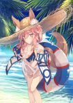  1girl animal_ears bangs beach bikini blush breasts clouds commentary_request fate/grand_order fate_(series) fox_ears fox_girl fox_tail hair_between_eyes hair_tie hat highres holding innertube large_breasts long_hair looking_at_viewer low_ponytail nagishiro_mito ocean outdoors palm_tree pink_hair see-through sidelocks sky solo standing straw_hat swimsuit tail tamamo_(fate)_(all) tamamo_no_mae_(swimsuit_lancer)_(fate) tree yellow_eyes 