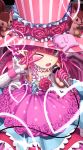 1girl ;d absurdres arm_up bangs blue_eyes blush commentary_request dress elizabeth_bathory_(fate) elizabeth_bathory_(fate)_(all) eyebrows_visible_through_hair fangs fate/extra fate/extra_ccc fate_(series) flower hair_between_eyes hand_up hat heart highres holding holding_microphone looking_at_viewer microphone one_eye_closed open_mouth pink_dress pink_flower pink_hair pink_hat pink_rose pointy_ears polka_dot polka_dot_dress red_flower red_rose rose sanbe_futoshi skull smile solo striped top_hat v_over_eye vertical-striped_hat vertical_stripes 