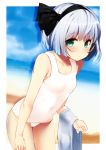  1girl bangs bare_arms bare_shoulders beach black_hairband black_ribbon blue_sky blush border breasts collarbone commentary_request covered_navel cowboy_shot day eyebrows_visible_through_hair green_eyes hair_ribbon hairband highres holding holding_towel konpaku_youmu leaning_forward looking_at_viewer nigo_(aozoragarou) outdoors outside_border portrait ribbon sand shadow short_hair silver_hair sky small_breasts solo standing swimsuit thighs touhou towel water white_border white_swimsuit 