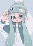  1girl adjusting_clothes adjusting_hat bangs beanie blunt_bangs commentary domino_mask gomi_(kaiwaresan44) green_coat green_hair green_hat hat inkling logo long_hair long_sleeves looking_at_viewer mask nintendo parted_lips pointy_ears smile solo splatoon splatoon_2 standing tentacle_hair upper_body 