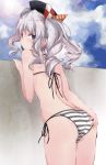  1girl ass ass_grab beret bikini black_hat blue_eyes blue_sky clouds commentary_request cowboy_shot day from_behind hat kantai_collection kashima_(kantai_collection) looking_at_viewer looking_back outdoors side-tie_bikini sidelocks silver_hair sky solo striped striped_bikini swimsuit tsurime twintails wall wavy_hair yumesato_makura 