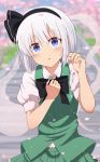  1girl absurdres arms_up bangs black_neckwear blue_eyes blurry blush bow bowtie cherry_blossoms day depth_of_field eyebrows_visible_through_hair green_skirt green_vest hair_between_eyes hair_ribbon hand_on_own_chest head_tilt highres holding_petal konpaku_youmu konpaku_youmu_(ghost) leaning_over looking_at_viewer outdoors parted_lips petals puffy_short_sleeves puffy_sleeves ribbon shirt short_hair short_sleeves silver_hair skirt sleeve_cuffs solo stairs standing taki_sandstone touhou upper_body vest white_shirt 