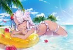  1girl bangs bare_shoulders beach bikini blue_sky blush bracelet breasts chloe_von_einzbern collarbone dark_skin fate/kaleid_liner_prisma_illya fate_(series) flower garter_straps hair_between_eyes hair_flower hair_ornament hibiscus highres index_finger_raised innertube jewelry long_hair looking_at_viewer lying necklace ocean on_stomach one_side_up open_mouth orange_eyes palm_tree pink_hair sky small_breasts smile solo sparkle swimsuit thighs tree white_bikini yuge_(mkmk) 