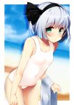  1girl absurdres bangs bare_arms bare_shoulders beach black_hairband black_ribbon blue_sky blush border breasts collarbone covered_navel cowboy_shot day eyebrows_visible_through_hair fanbox_reward green_eyes hair_ribbon hairband highres holding holding_towel konpaku_youmu leaning_forward looking_at_viewer nigo_(aozoragarou) outdoors outside_border paid_reward ribbon sand shadow short_hair silver_hair sky small_breasts solo standing swimsuit thighs touhou towel water white_border white_swimsuit 