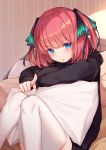  1girl bison_cangshu black_hoodie blue_eyes go-toubun_no_hanayome hair_ornament highres hood hood_down hoodie knees_together_feet_apart knees_up long_sleeves looking_at_viewer nakano_nino parted_lips pillow pink_hair pointing pointing_at_viewer short_hair sitting solo thigh-highs two_side_up white_legwear 