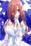  1girl arm_at_side bare_shoulders blue_eyes blue_flower blush commentary_request dress elbow_gloves eyes_visible_through_hair finger_to_mouth floral_background flower gloves go-toubun_no_hanayome hair_over_one_eye headphones headphones_around_neck long_hair looking_at_viewer nakano_miku necocafe_lili parted_lips redhead smile solo strapless strapless_dress upper_body wedding_dress white_dress white_gloves white_headwear 