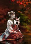  1girl autumn_leaves bangs brown_hair commentary_request fox_hair_ornament fox_mask hair_bun hair_ornament hakama highres holding holding_mask japanese_clothes leaf long_sleeves mask original parted_lips profile red_hakama reflection seiza sitting solo wide_sleeves xiaobanbei_milk 