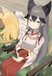  2girls absurdres animal_ear_fluff animal_ears bangs black_hair blonde_hair brown_eyes card extra_ears ezo_red_fox_(kemono_friends) facing_away fox_ears fox_girl gradient_hair grey_hair hair_between_eyes hakama_skirt handheld_game_console highres hip_vent japanese_clothes kemono_friends kemono_friends_3 long_hair looking_at_viewer lying miko mochorinpun multicolored_hair multiple_girls on_side silver_fox_(kemono_friends) sitting smile wide_sleeves 